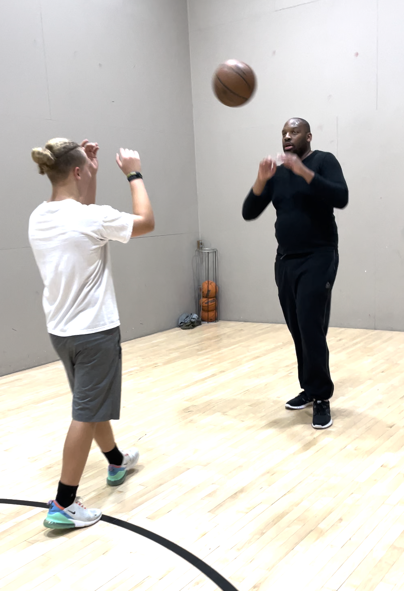 Coach Kaimyn training a youth player on court